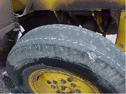 Photo 12.  Left rear-steer whieel.  Note the large chunk of rubber and most tread missing.