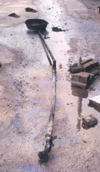 Photo 2 – Articulated pipe with oil pan on one end, and broken fitting for the oil barrel on the other.