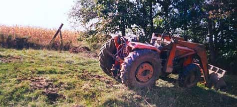 Photo 1 – View of the scene showing the fence being repaired, the sloping pasture, and the up-righted tractor.