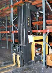 Photo 1 - Left-front view of the forklift, positioned as it was found under the empty metal rack beam.