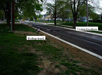 Mishap site looking south. Note dotted line showing location of parked pickup truck and arrow indicating victim’s location when struck.