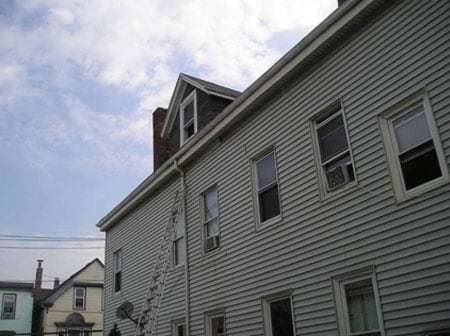 Neighboring house where the incident took place. Note the loose piece of vinyl siding to the right and above the top of the ladder.