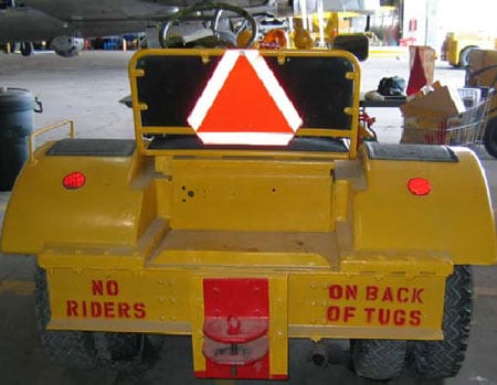 Back of aircraft tug showing storage area and rider warning.