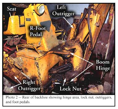 Photo 2 -- Rear of backhoe showing hinge area, lock nut, outriggers, and foot pedals