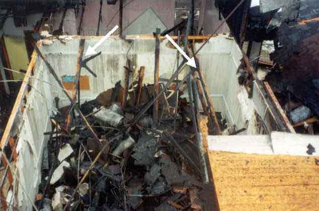 Photograph of burned-out structure, showing truss and gusset plates.
