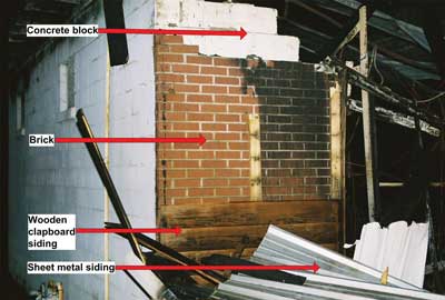 Left front corner of fire building; 4 different layers of construction materials used on front wall can be clearly seen; Collapse area is to right.