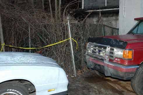 Photograph 2. Hose line stretched 200 feet toward the rear of the structure onto pickup truck and over 6-foot fence.
