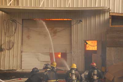 Fire fighters fight the fire from outside the warehouse