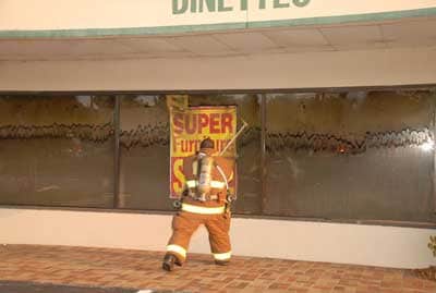 Fire fighter about to break a window of a smoke filled room.