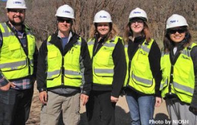 Four NIOSH investigators and one resident rotator take a group photo while wearing hard hats and reflective vests during a site visit in Utah
