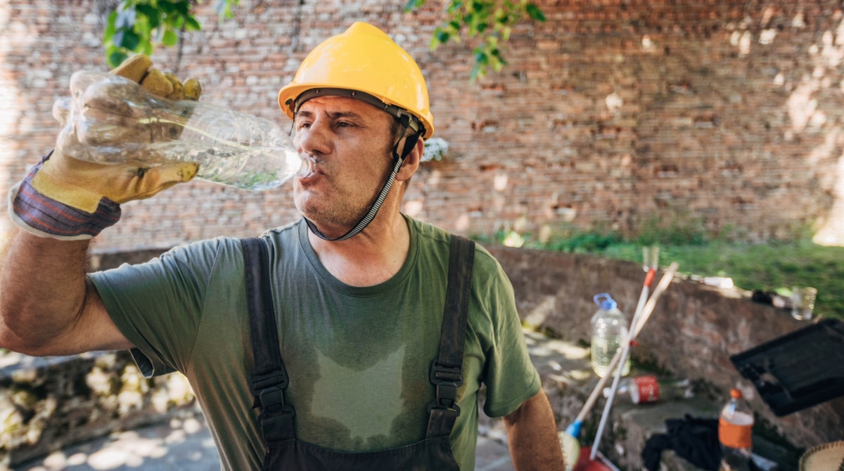 Outdoor worker sweating and drinking water