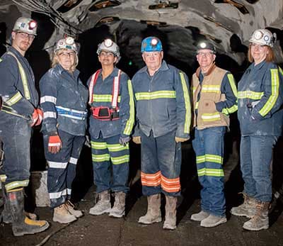 Images of six mine workers wearing protective gear in a mine