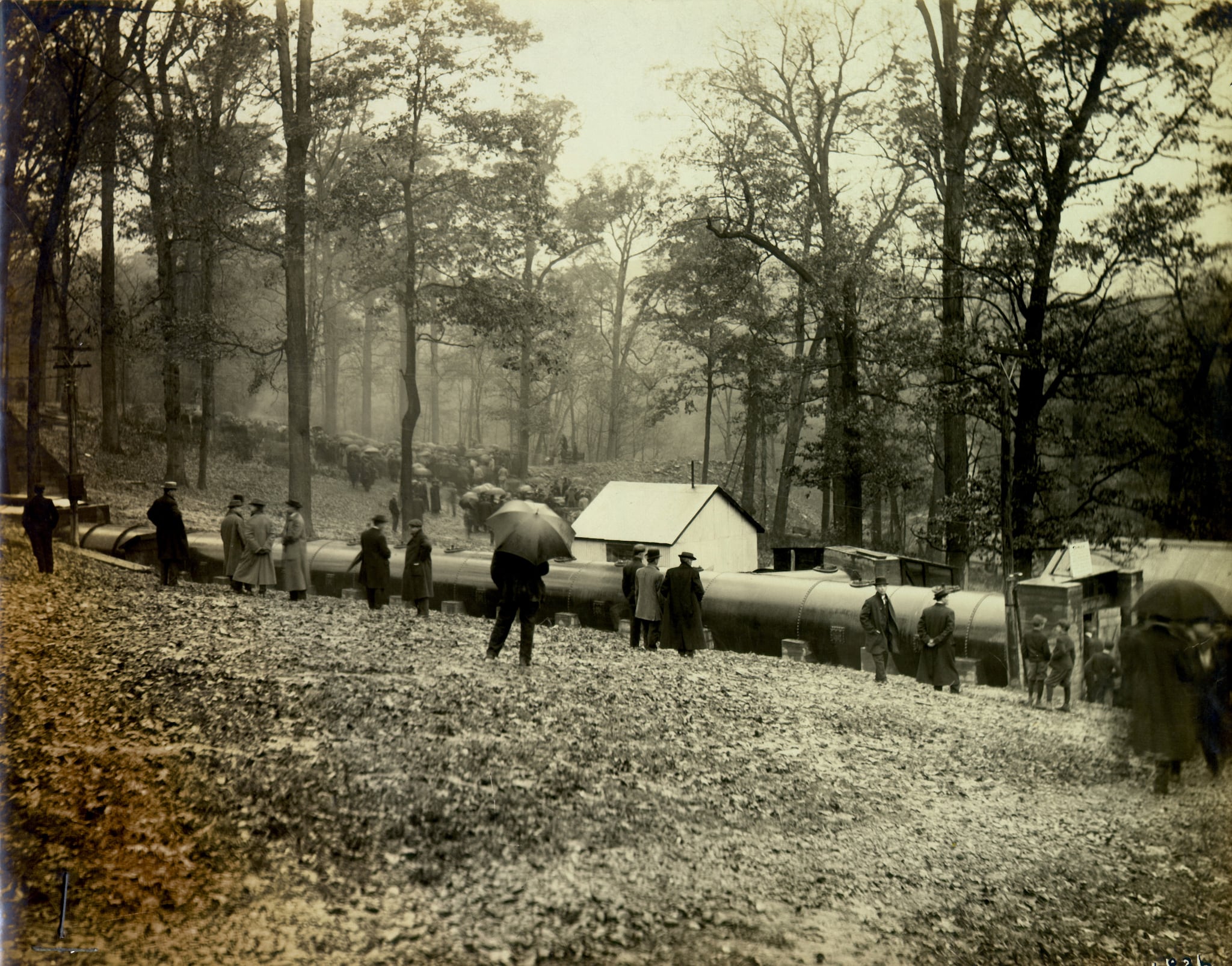 Historical photo of spectators with umbrellas gathering to watch testing outdoors