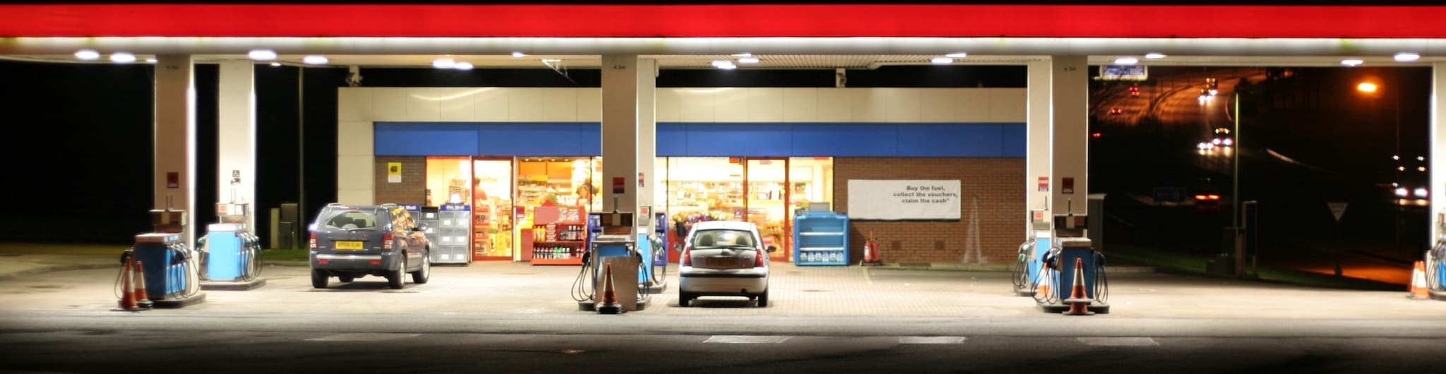 gas station at night with 2 cars at the pumps