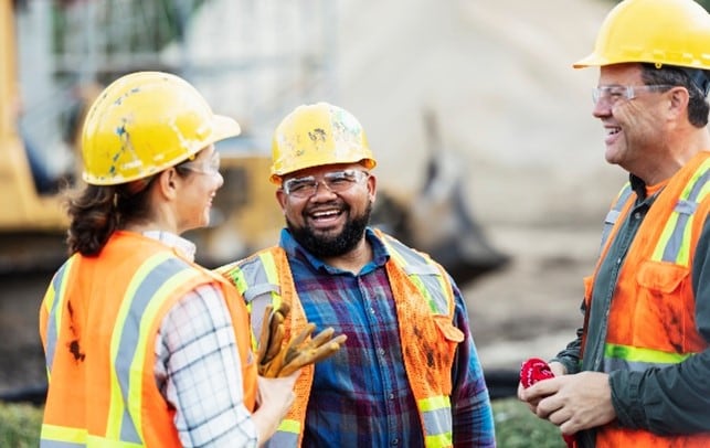 three workers in a conversation wearing safety helmets