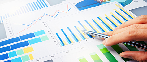 A man hand holding a pen pointing to graphs