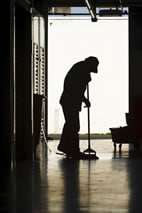 Silhouette of a janitor mopping a floor in a factory