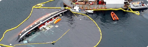 Aerial photo of a partially submerged commercial fishing vessel with oil containment booms surrounding the vessel. Photo by USCG