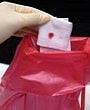 Gloved hand disposing of blood-stained gauze pad