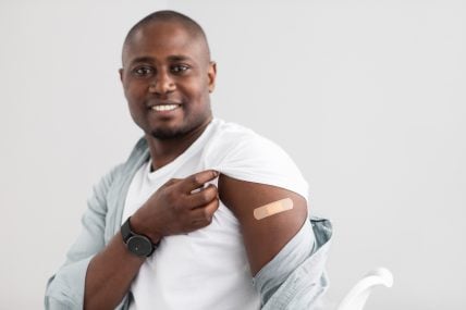 Man showing the bandage after coronavirus vaccine shot
