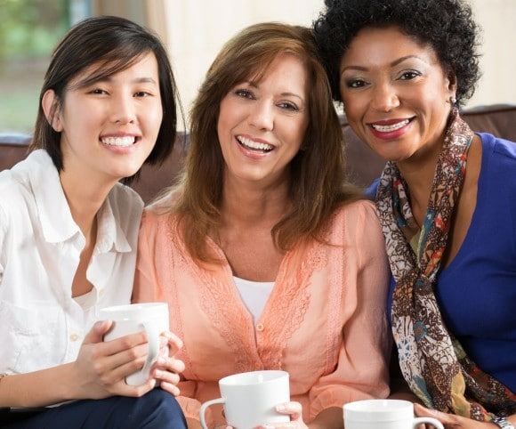 Three woman smiling and drinking coffee