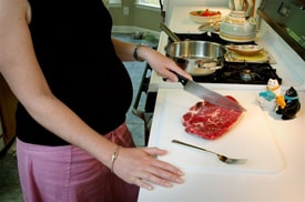 Picture of a woman cutting a piece of raw meat.