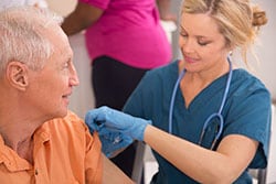 Doctor injecting an older patient with a vaccine