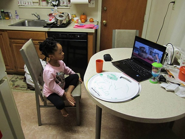 Child sitting at a kitchen table watching a movie on a computer