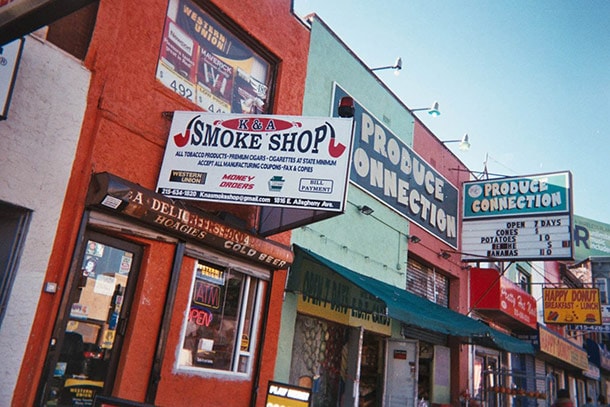 Street scene showing a smoke shop next door to a store selling produce