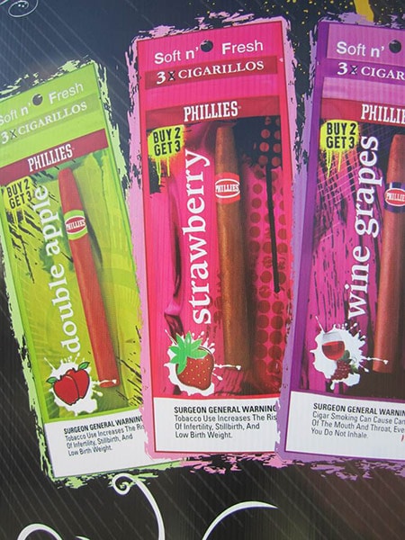 Part of a sign showing colorful packages of cigarillos with apple, strawberry, and grape flavorings