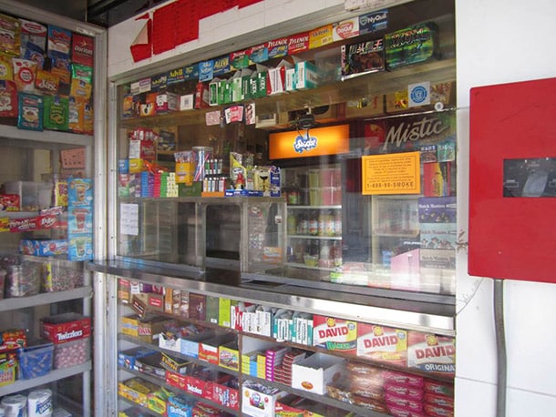 A convenience store counter and shelf display of candy and cigarettes
