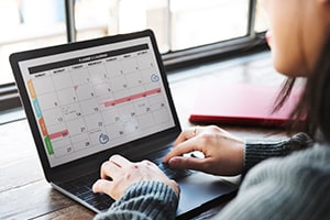 Lady sitting with laptop looking at monthly calendar
