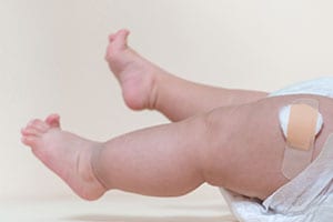 piernas de un niño bebé con una cura después de recibir una vacuna