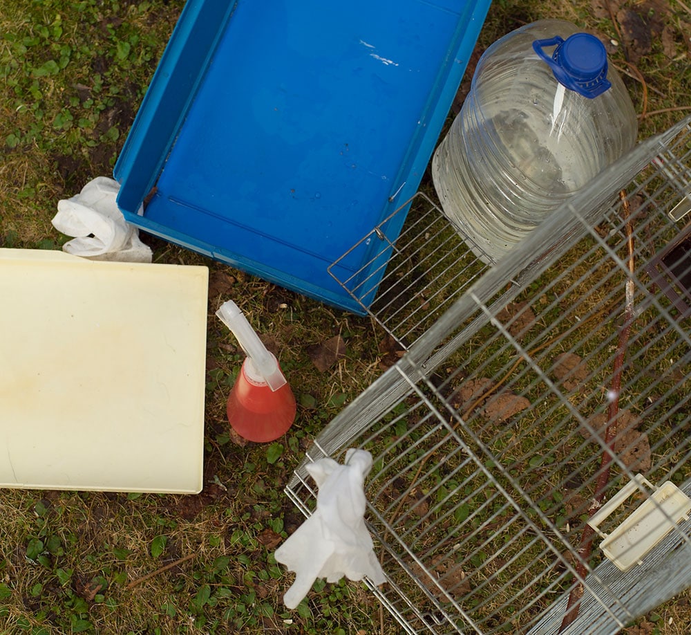 Overhead shot of a pet cage parts on the ground separated for cleaning.