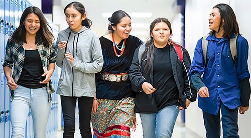American Indian youths walking through the halls of a school.