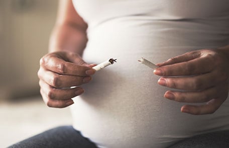 Pregnant woman holding broken cigarette
