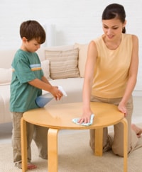 Un niño y su mamá limpiando una mesa