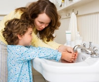 Mamá lavando las manos de su hijo
