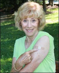 Mujer indicando el área de la vacuna en su brazo 
