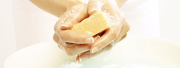 Manos de mujer lavándose con una barra de jabón.