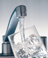 Agua saliendo de un grifo llenando un vaso de cristal