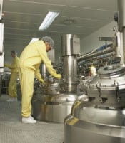 Un hombre que lleva traje amarillo para protejer contra productos químicos que gira la rueda de una máquina.