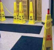 Cadena amarilla de seguridad colgada entre dos señales de piso mojado amarillas en forma de cono