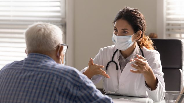 Close up female therapist wearing face mask consulting mature patient