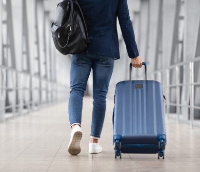 Man walking through airport pulling luggage
