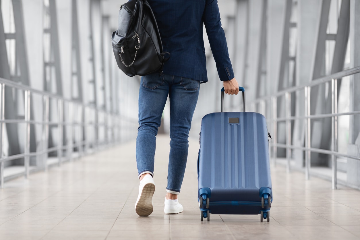 Man walking through airport pulling luggage