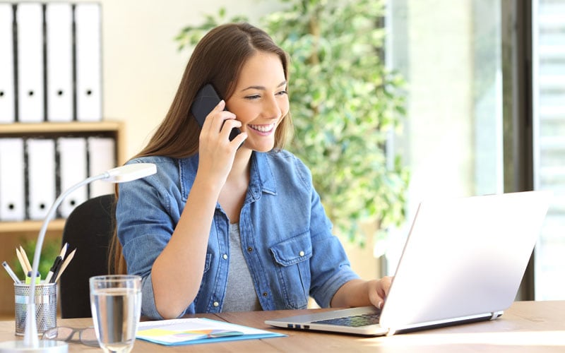 How do I know using a quitline will help? Happy woman on phone looking at her laptop.