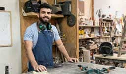 Hombre en un taller de carpintería sonriendo