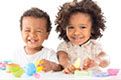 Two babies smiling and playing with colorful toys