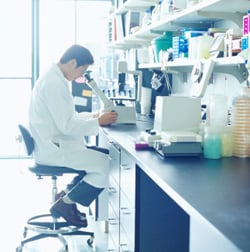 man in a laboratory looking into a microscope